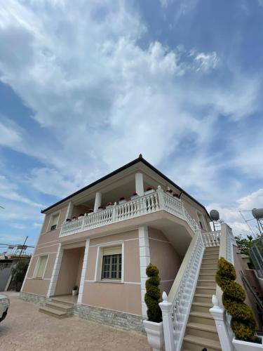 伏罗拉Rent rooms Loren的粉红色的房子设有白色阳台和楼梯