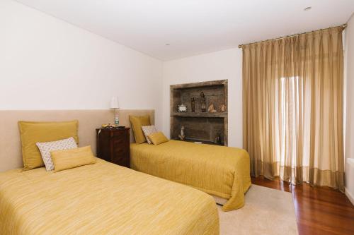 阿尔瓦伦加Casa do Passadiço - Alvarenga的一间卧室设有两张带黄床单的床和窗户。