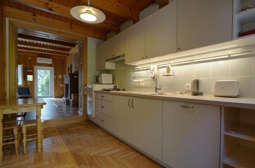内林加Forest Cottage的一间铺有木地板的大厨房,配有白色的橱柜