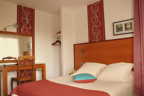 旺多姆Hotel Capricorne的一间卧室配有一张带木制床头板和一张桌子的床。