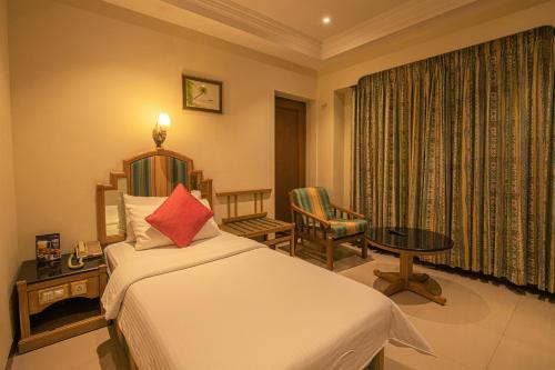 哥印拜陀CAG普莱德酒店的卧室配有1张床、1张桌子和1把椅子