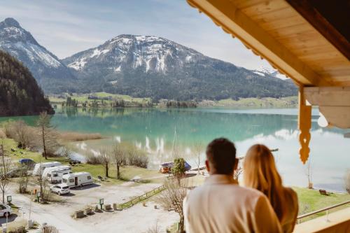 圣沃尔夫冈Seehotel Berau的一对夫妇从窗户望向湖泊和山脉