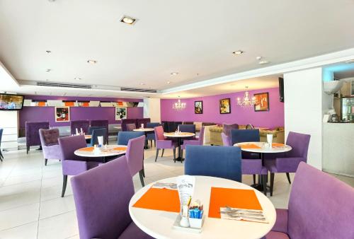 芭堤雅市中心Nova Suites Pattaya by Compass Hospitality的一间带桌子和紫色椅子的用餐室