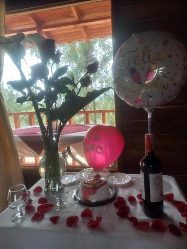 瓜塔维塔Cabaña Sueños Dorados的一张带玫瑰的桌子和一瓶葡萄酒,还有插花