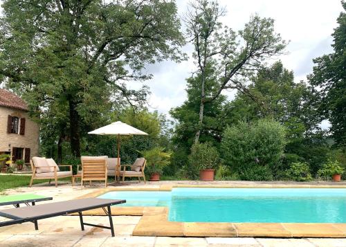Lissac et MouretLes cabanes de Julie的一个带桌椅和遮阳伞的游泳池