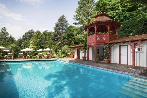 梅拉诺卡斯特尔弗莱堡瑞莱斯城堡酒店的一座游泳池,毗邻一座建筑,设有凉亭