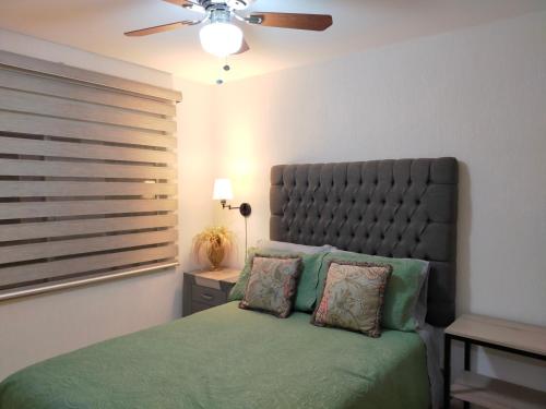 瓜达拉哈拉Luxury Department Tlaquepaque的一间卧室配有一张绿色的床和吊扇