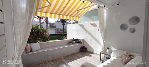 德尔锡伦西奥海岸Ideal holiday apartment in the south of Tenerife的阳台配有沙发和黄色及白色的天篷