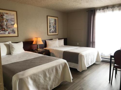 七岛市Hôtel Mingan的酒店客房设有两张床和窗户。