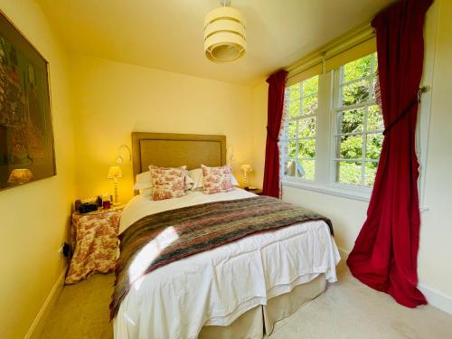 HurlfordCarnell Country Estate的一间卧室配有一张带红色窗帘的床和一扇窗户