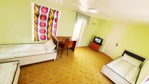 布哈拉Soliha&Yulduz Guesthouse的客房设有两张床、一张桌子和一扇窗户。