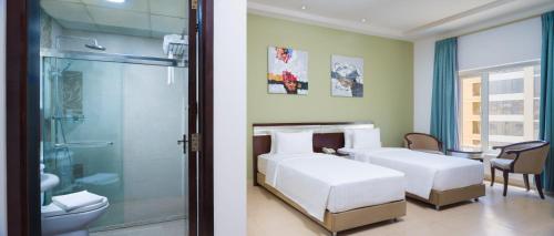马斯喀特Centara Life Muscat Dunes Hotel的配有2张床的客房设有淋浴和浴室。