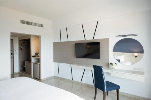 七岩Centara Life Cha-Am Beach Resort Hua Hin的一间卧室配有一张床、一台电视和一张蓝色椅子