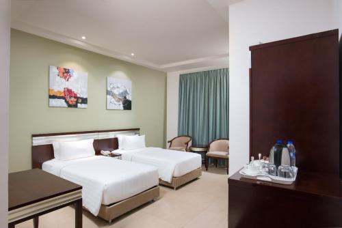 马斯喀特Centara Life Muscat Dunes Hotel的酒店客房设有两张床和一张桌子。