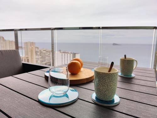 贝尼多姆SUNSET WAVES sea & sky apartment的一张木桌,上面有两杯和橙子