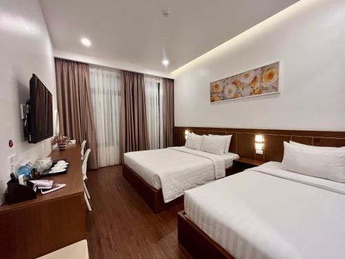 绥和市Marina Hotel Phú Yên的酒店客房设有两张床和电视。