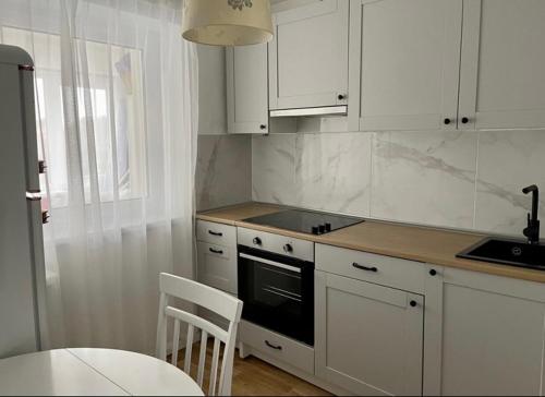 纳尔瓦约埃苏N-J APARTANENT的厨房配有白色橱柜、桌子和炉灶。