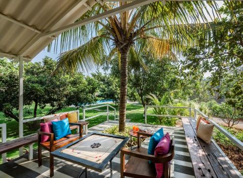 卡尔贾特SaffronStays Casa Manga, Karjat - pet-friendly pool villa near ND's Film World and Saltt的一个带桌椅和棕榈树的庭院