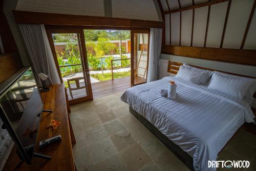 塞隆贝拉纳克Driftwood Lombok的一间带大床的卧室和一个阳台
