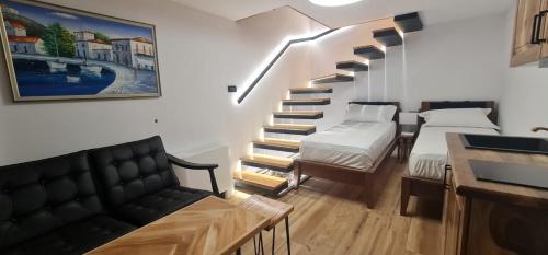 波格拉德茨Bujtina Gjyshi Ilo的客房设有带两张床和一张沙发的楼梯。