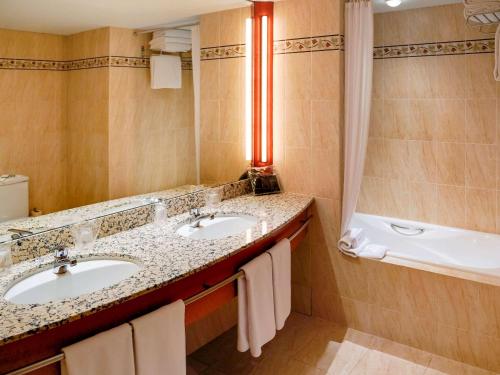 安道尔城安道尔美居酒店的浴室配有2个盥洗盆和1个浴缸。