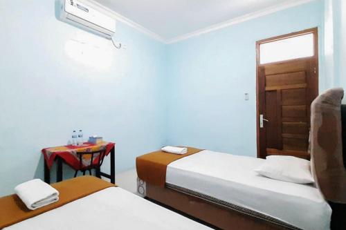 Tua PejatPrima Homestay Mentawai Mitra RedDoorz的客房设有两张床和一张带窗户的桌子。