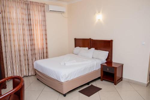 马普托Pensao Marhaba Residencial的一间卧室配有一张大床和一个床头柜