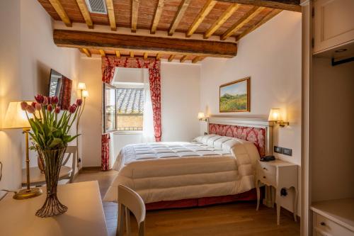 蒙特普齐亚诺Palazzo del Mercante的一间卧室配有一张床、一张桌子和一个窗户。