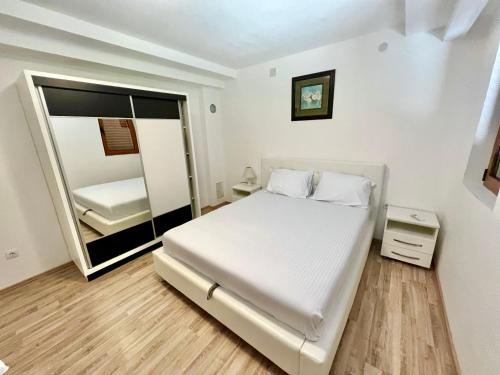 蒂瓦特Apartments Family的白色卧室配有床和镜子