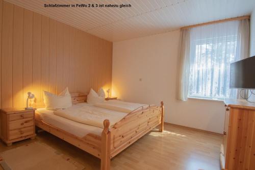 于克里茨Dünenhaus Fewos - Zum Strand 50m的一间卧室设有一张木床、一台电视和一扇窗户。
