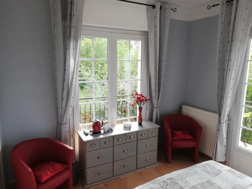 TournayLESSENCIEL的一间卧室配有2把红色椅子、梳妆台和窗户