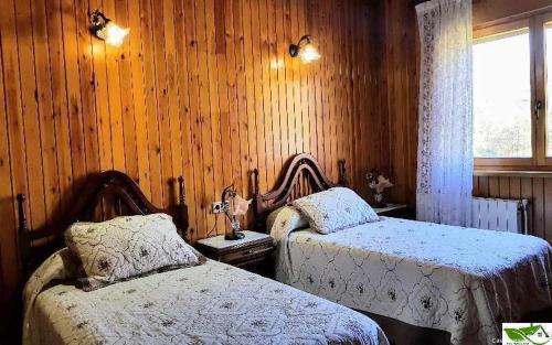 利亚内斯Casa Vacacional Mari Paz的一间卧室设有两张床、一个窗口和木墙