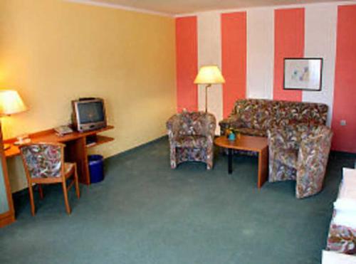 LankenTOP Motel Sassnitz的带沙发、桌子和电视的客房