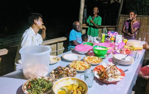 KriGibran guest house的一群人坐在桌子旁吃着食物
