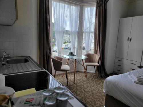 斯卡伯勒Seaside ground floor flat WIFI & FREE parking的酒店客房设有厨房、一张床和一张桌子。