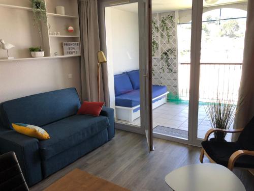 杜瓦讷内Très bel appartement vue mer avec piscine的客厅设有蓝色的沙发和滑动玻璃门