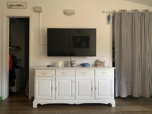 阿祖罗港Appartamento La casa di Chiara的墙上的白色橱柜和平面电视