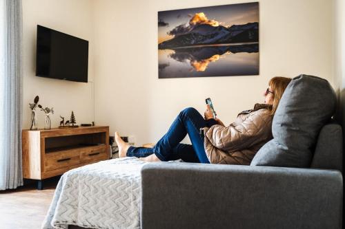索尔德乌Apartamento Luxury en Bordes d'Envalira, Andorra的坐在沙发上拿着手机的女人