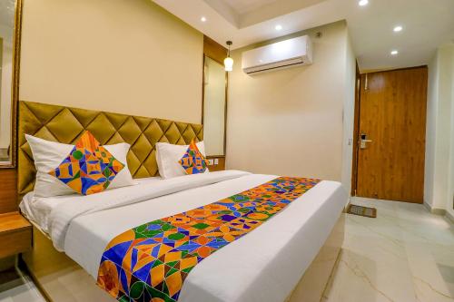 新德里FabHotel F9 Pitampura的一间卧室配有一张大床和色彩缤纷的毯子