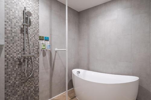台中市台中凤凰酒店的浴室配有白色浴缸和淋浴。