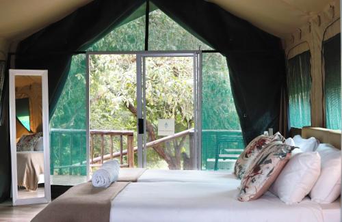 雾观Lions Rock Rapids - Luxury Tented Camp的一间卧室设有一张大床和大窗户