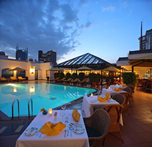 内罗毕萨洛瓦士丹利酒店的餐厅设有一座带桌椅的游泳池