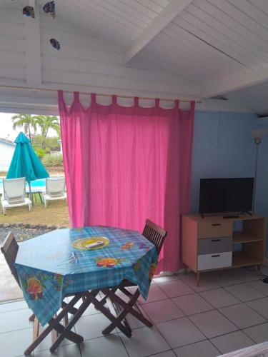 勒穆莱Les Gîtes Hoprins的一张桌子和椅子,位于一个粉红色窗帘的房间