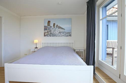 博尔滕哈根Dünenblick Wohnung 51的白色的卧室设有床和窗户