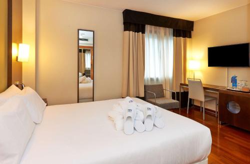 萨拉戈萨斯波特NH酒店的酒店客房,配有带毛巾的床