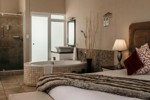 斯瓦科普蒙德Artemis Hotel Swakopmund的一间带浴缸、一张床和一个水槽的卧室