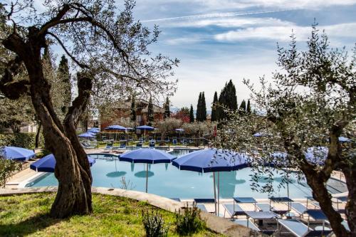 特拉西梅诺湖畔帕西尼亚诺Hotel Villa Paradiso的一个带蓝伞和椅子的游泳池