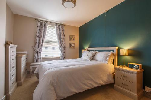 谢林汉姆Mabel Cottage Sheringham的一间卧室设有一张大床和蓝色的墙壁