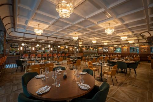 都柏林The Samuel Hotel的餐厅设有桌椅和吊灯。