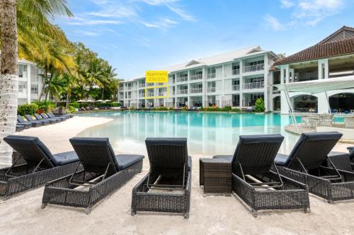 道格拉斯港Beach Club Port Douglas Luxury Apartments的酒店前方的游泳池配有椅子